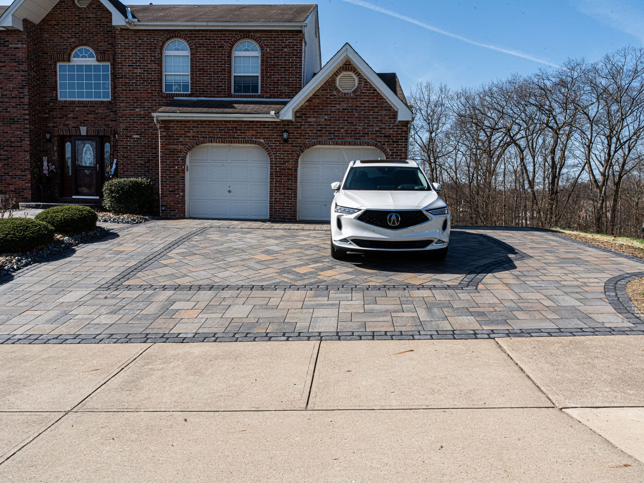 Paver driveway with a cobbled border leading to a two-car garage