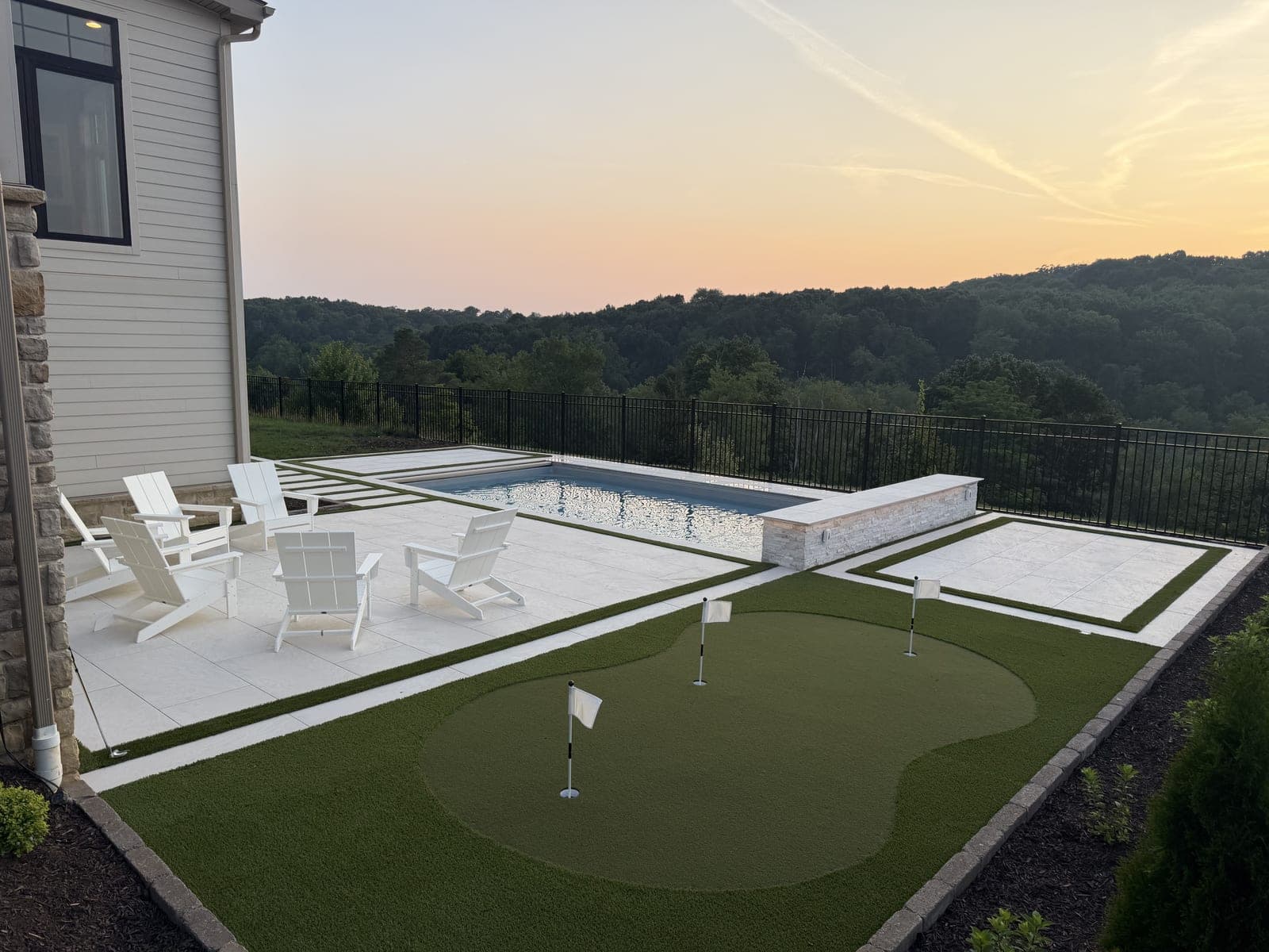 Pool, putting green, and outdoor seating at sunset