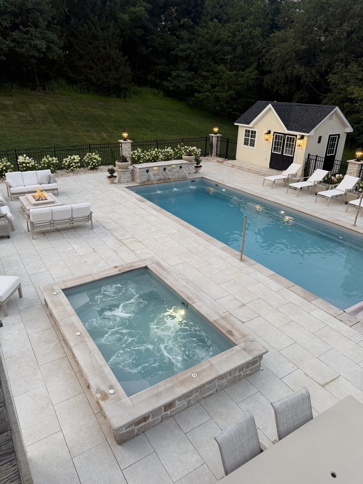 Bubbling spa jets with pool and pool house at dusk
